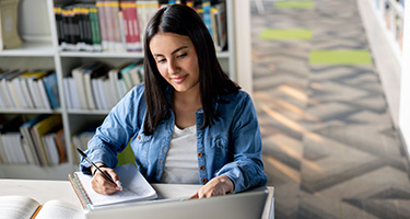 Online student working on laptop from library