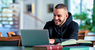 Online student working on laptop from library