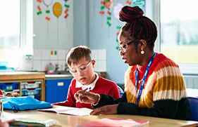 Teacher working on notebook with young student