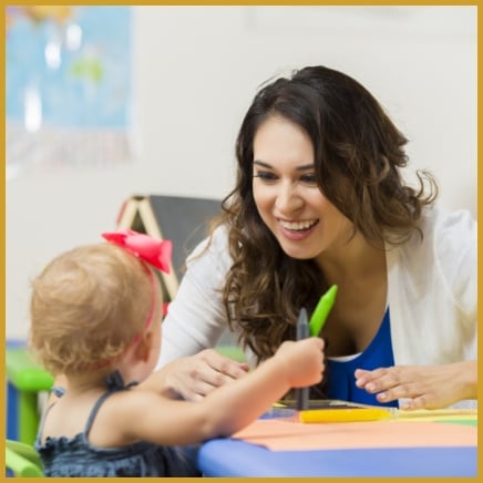 Teacher smiling and helping toddler
